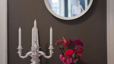 Flur: braune Wand, weißer Spiegel, weiße Kerzen